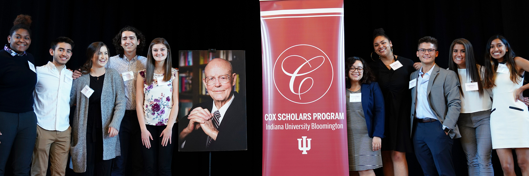 Cox Scholars standing next to a large photo of Jesse Cox